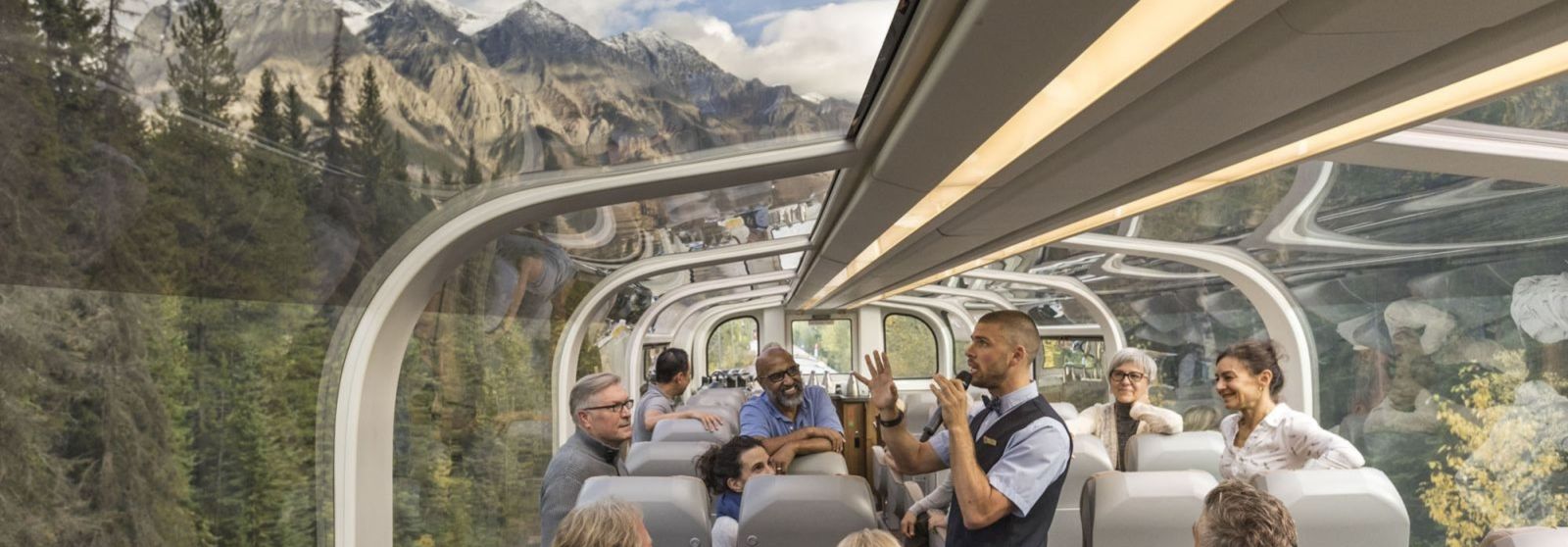 Rocky Mountain Train with panoramic windows with onboard guests listening to a tour guide