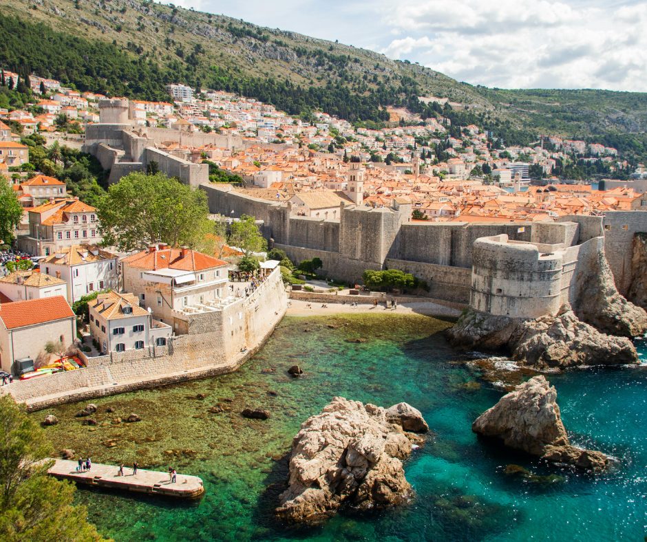 Large rocks emerge from the crystal clear coastline, opposite vibrant villages on the European coastline