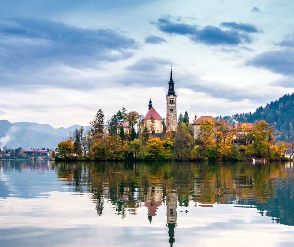 The still waters acts as a mirror, reflecting the tall steeple of the church on the island