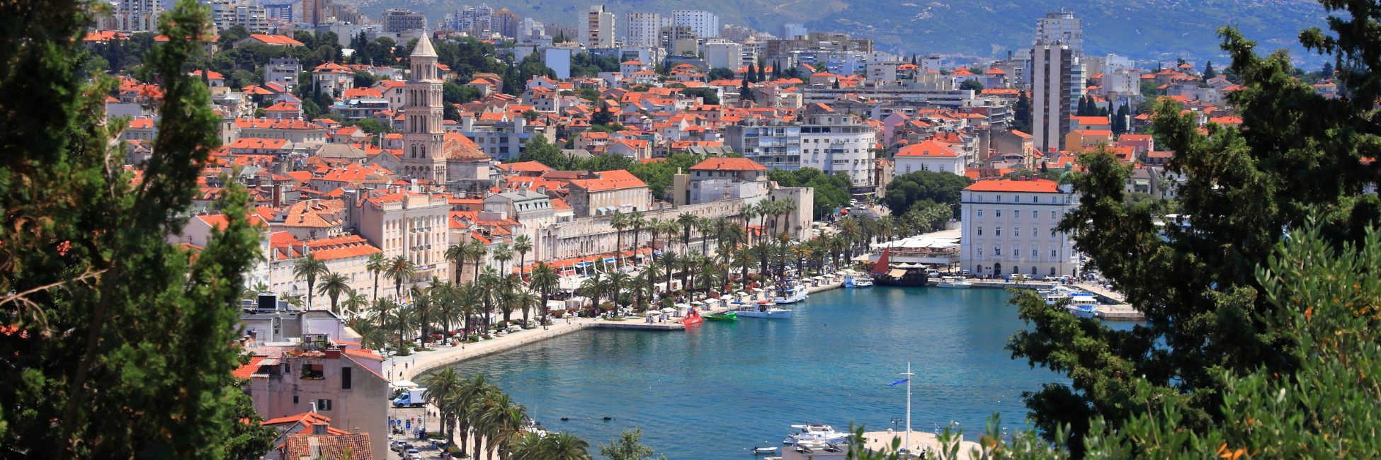 Croatian coastline with turquoise waters, rocky cliffs andseaside villages under a clear sky, showcasing the scenic beauty of a Croatia rail holiday