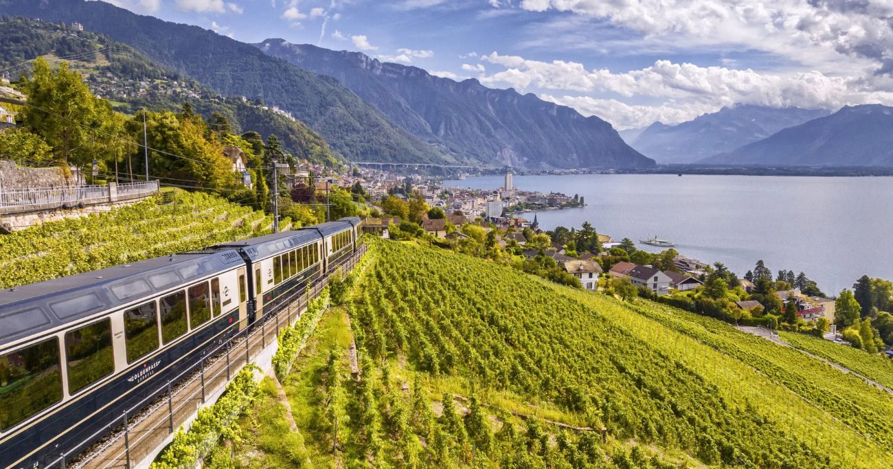 A train glides through the fresh Swiss landscapes